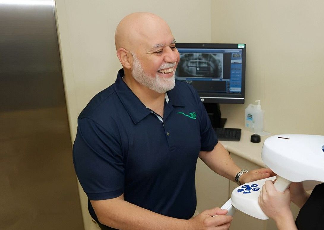 A Man is Talking to a Woman Who is Getting an X-ray of Her Teeth — Cairns Precision Dental Group In Woree, QLD