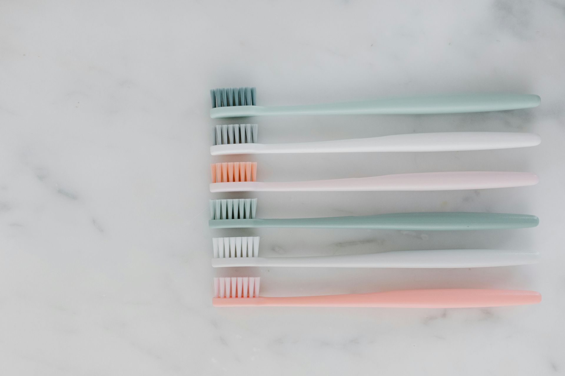 A Row Of Toothbrushes Are Lined Up In A Row On A White Surface — Cairns Precision Dental Group In Woree, QLD