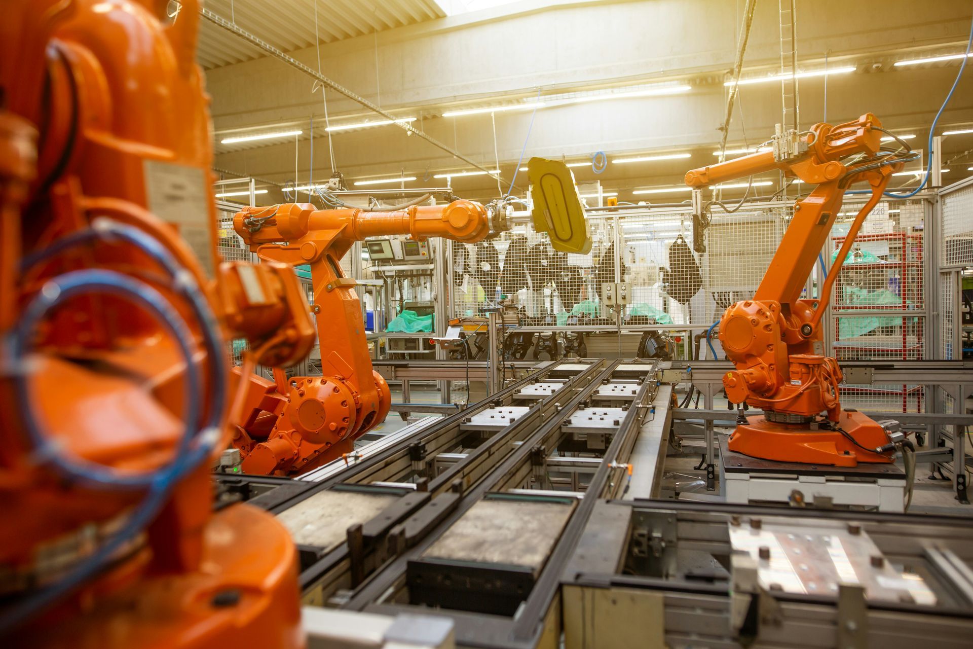 Orange robotic arms working on an assembly line in a factory.