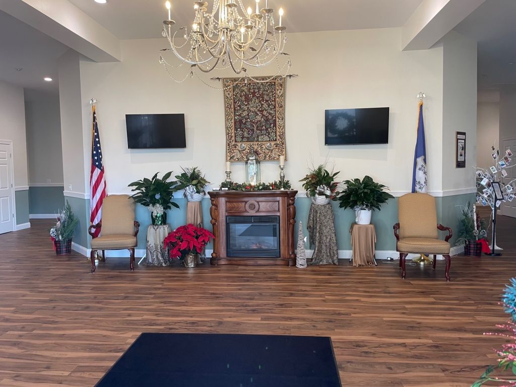A living room with a fireplace , chairs , flags and a chandelier.