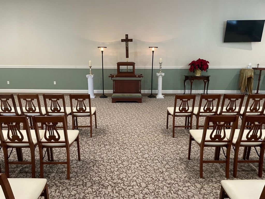 A room with rows of chairs and a cross on the wall.