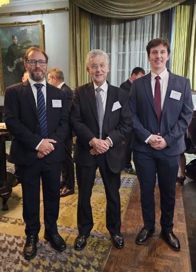Conference room with a stage, large screen displaying graphics, and tables.