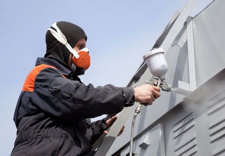 Painter in safety gear spraying paint on a commercial building. High-quality Dallas commercial painting services.