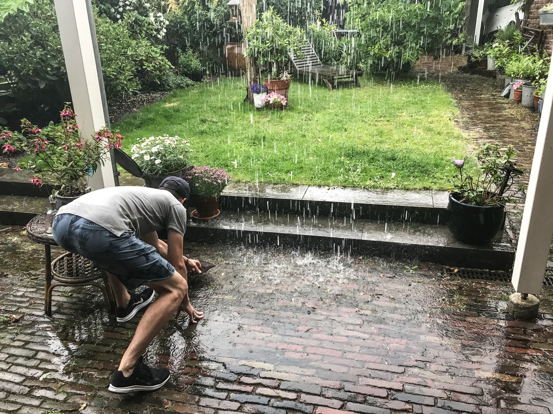 Man in achtertuin die regenwater opvangt