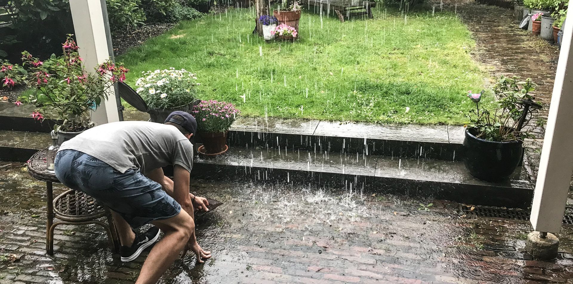 Man in achtertuin die regen opvangt / Regenwaterzuivering met Van Hall Innovations
