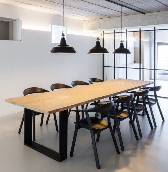 Ein langer Holztisch mit schwarzen Stühlen in einem Raum.