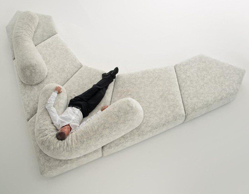 Ein Mann liegt auf einem großen weißen Sofa.