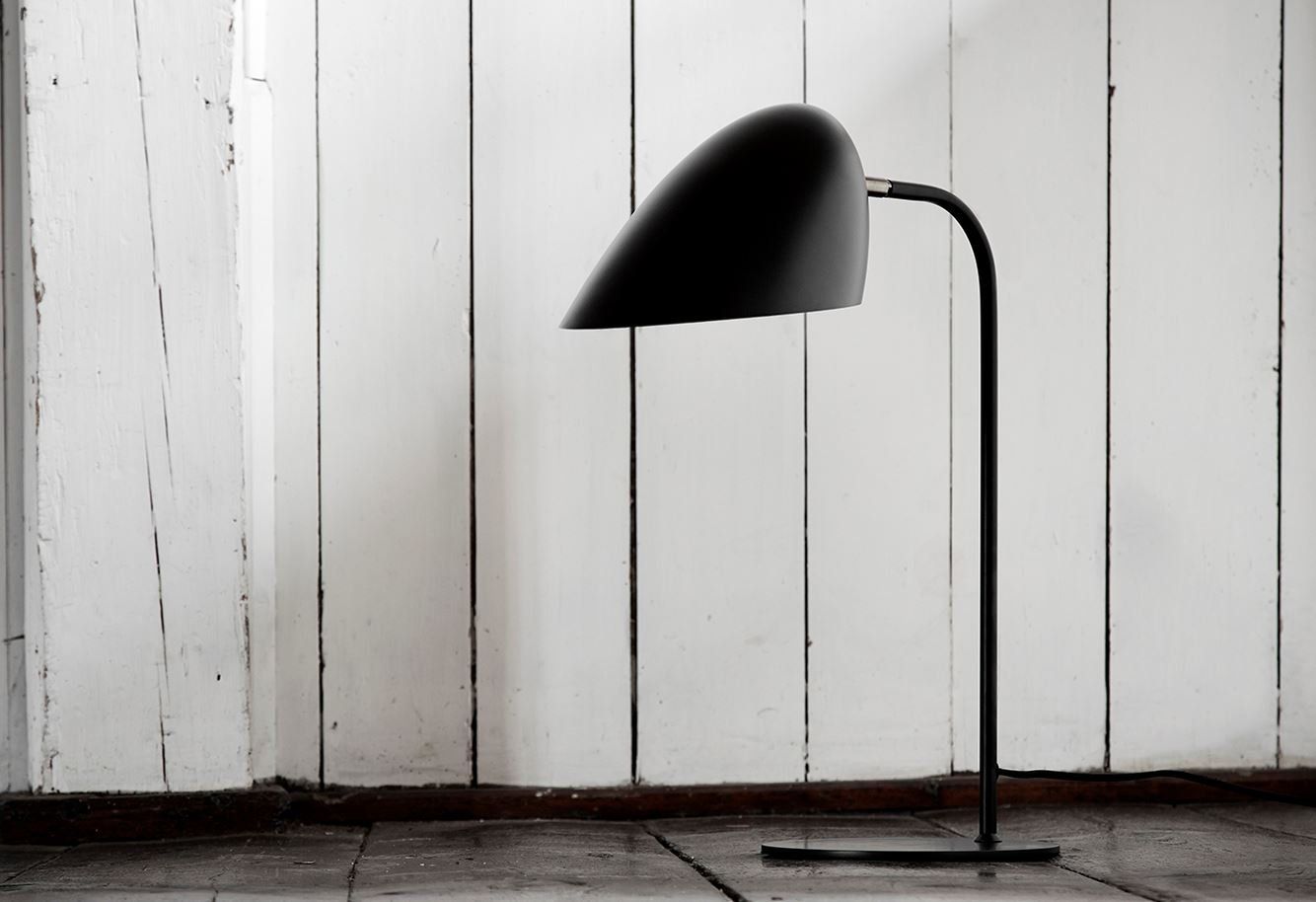 Eine schwarze Lampe steht vor einer weißen Wand