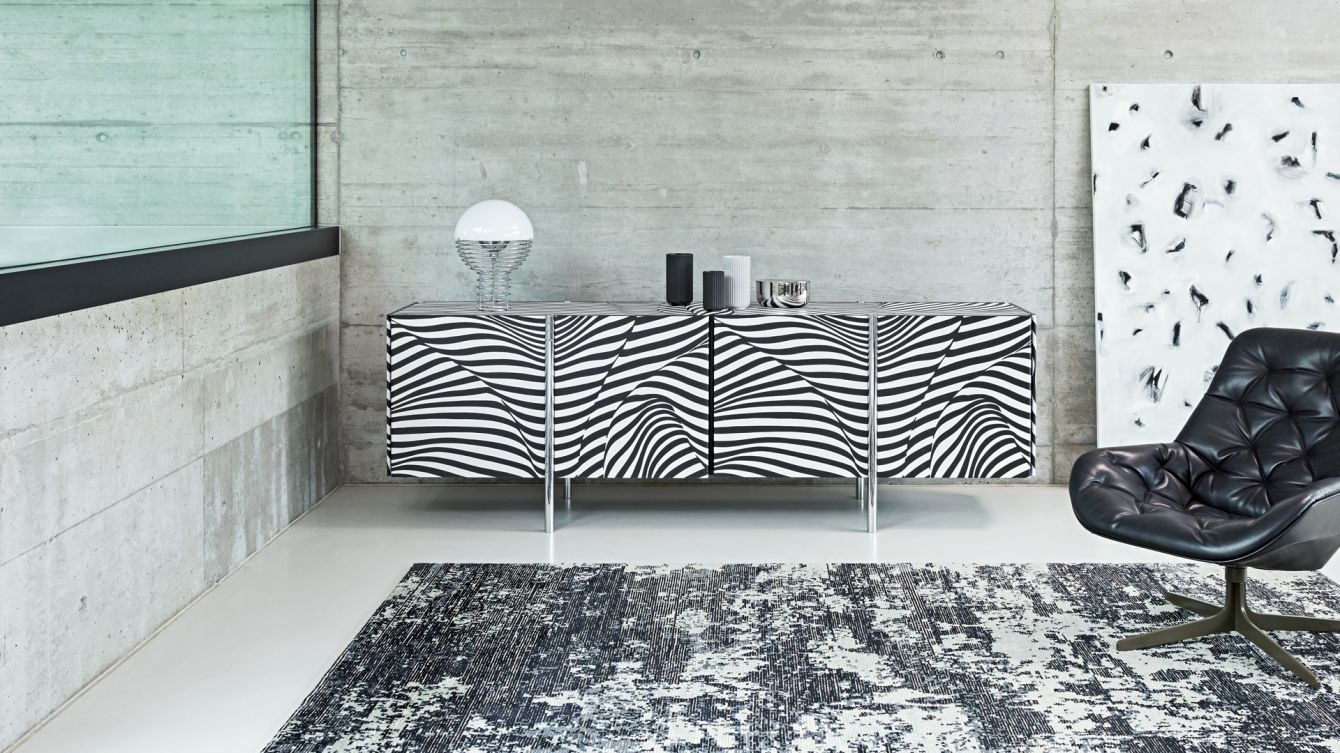 Ein schwarz-weißes Zimmer mit einer Kommode und einem Stuhl im Zebramuster