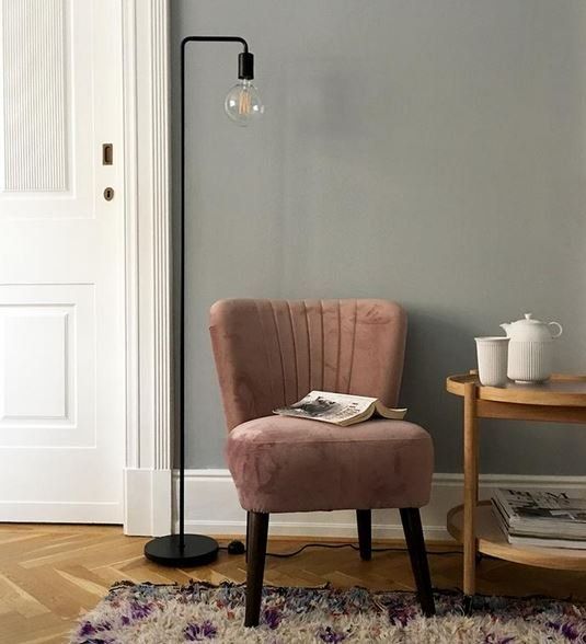 In einem Wohnzimmer steht ein rosa Sessel neben einerm Beistelltisch.