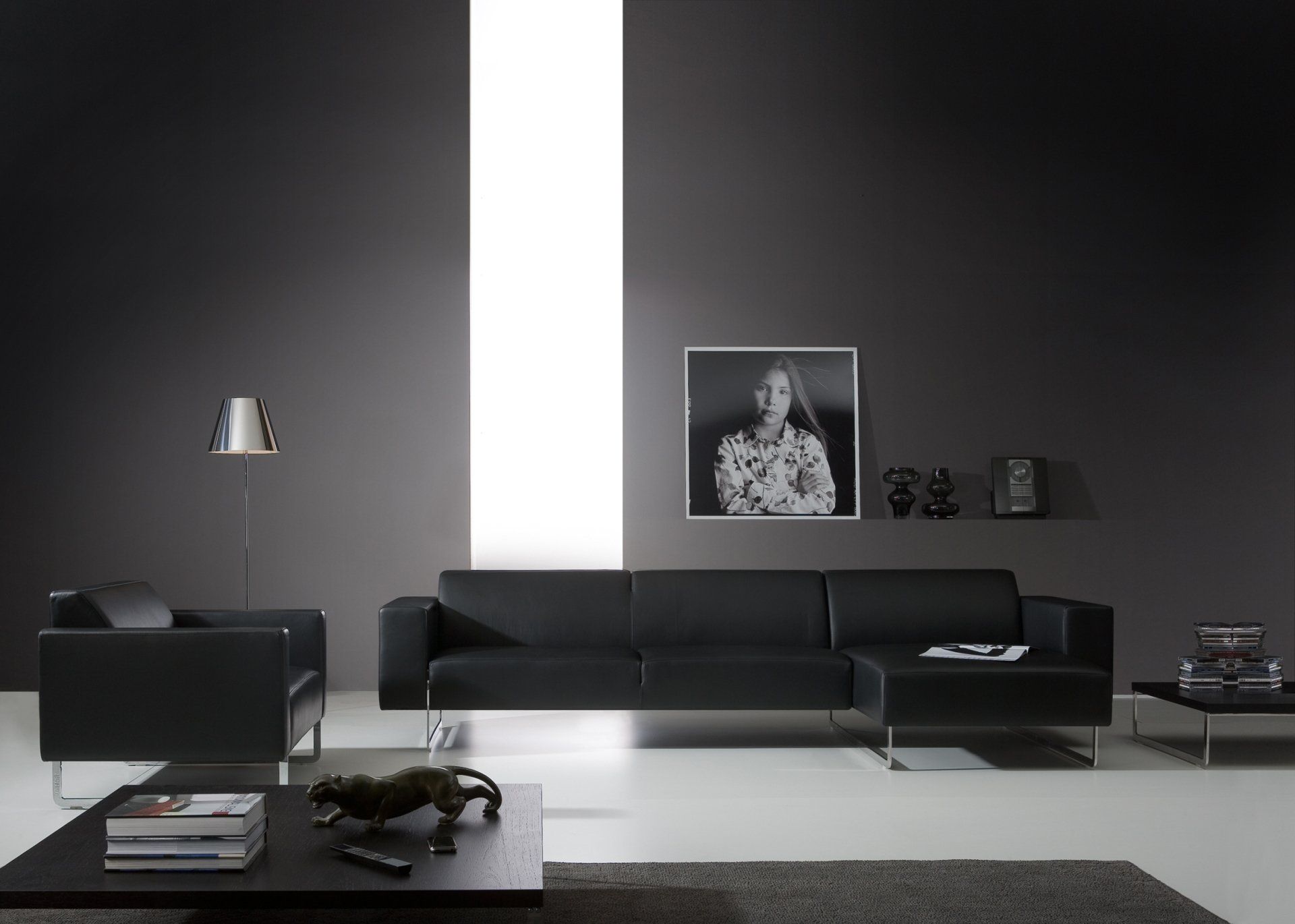 Ein Wohnzimmer mit schwarzen Möbeln und einem Bild an der Wand