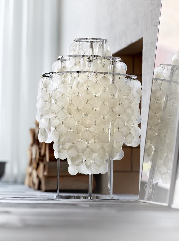 Eine weiße Lampe steht auf einem Tisch vor einem Spiegel