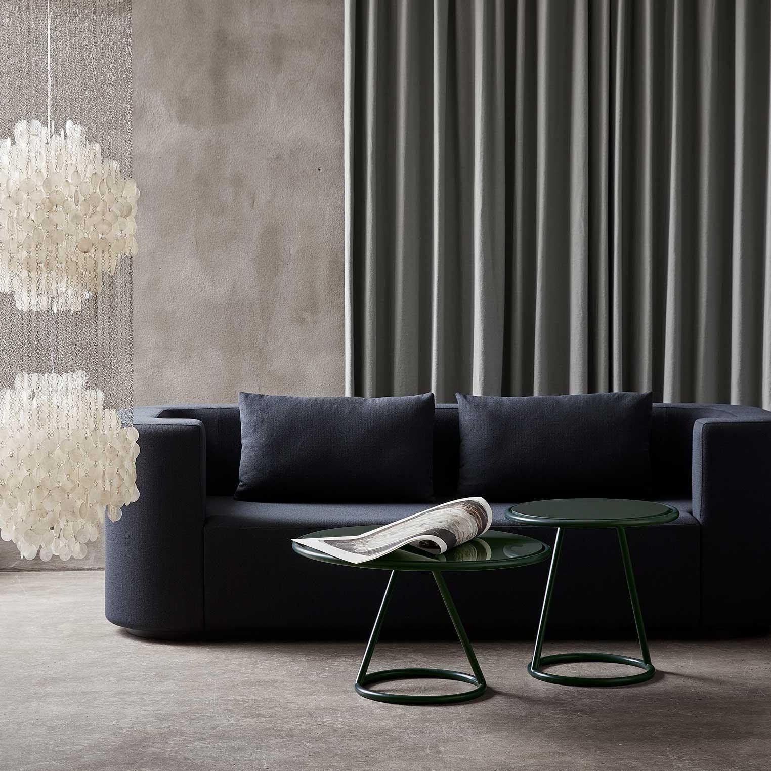 Ein Wohnzimmer mit einer schwarzen Couch und zwei grünen Tischen