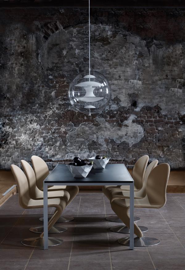 Ein Esszimmer mit Tisch und Stühlen vor einer Backsteinmauer