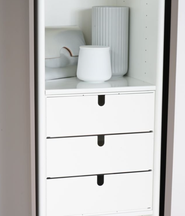 Ein Regal mit drei Schubladen und einer Vase darauf