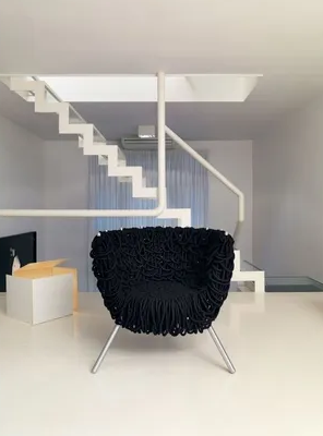 Ein schwarzer Stuhl steht vor einer weißen Treppe