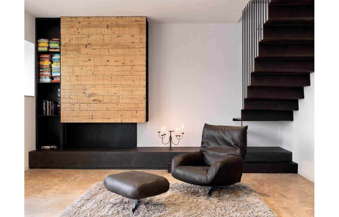 Ein Wohnzimmer mit Sessel, Ottomane und Treppe