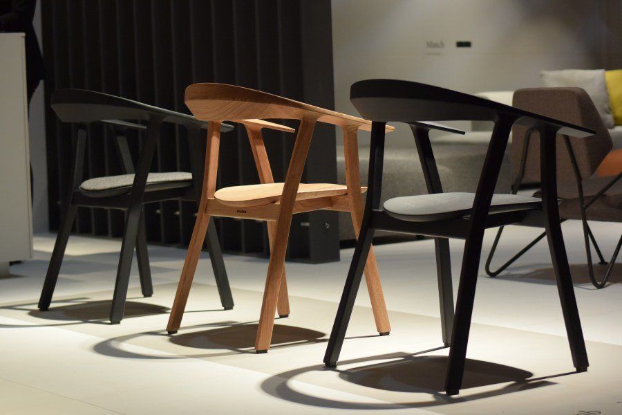 Drei Holzstühle stehen aufgereiht auf einem weißen Boden