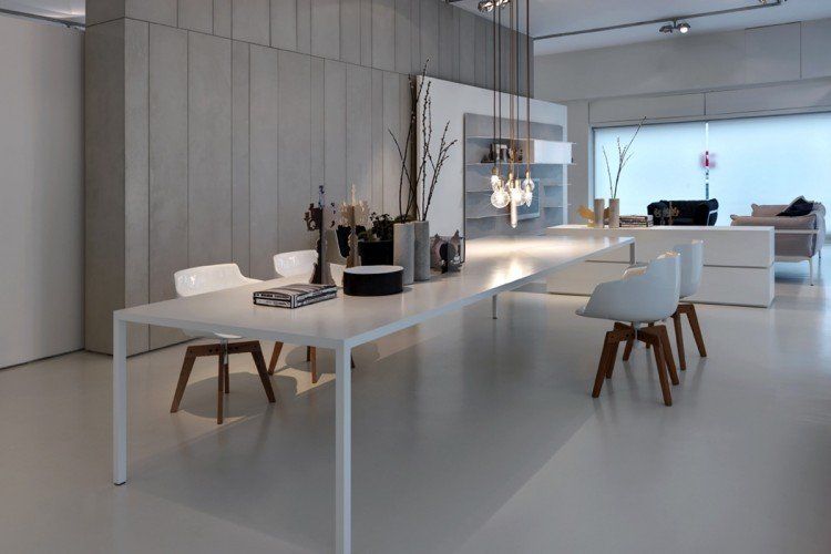 Ein Esszimmer mit einem langen weißen Tisch und Stühlen