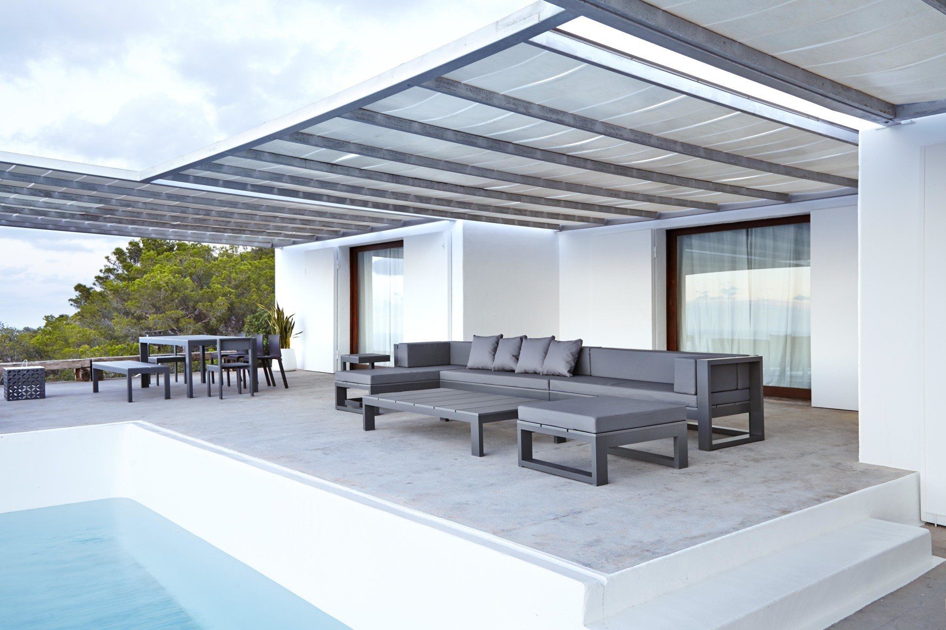 Eine Terrasse mit Sofa und Tischen unter einem Baldachin