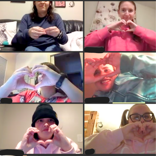 Six people on a video call forming heart shapes with their hands.