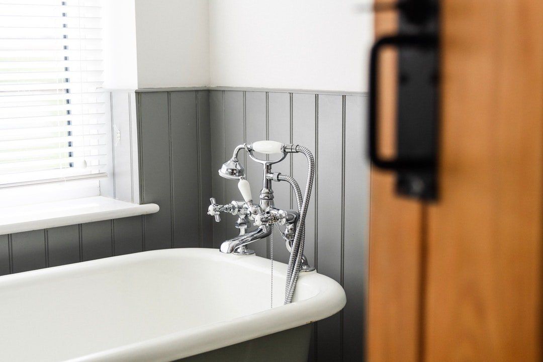 A bathtub with a shower head in a bathroom next to a window.