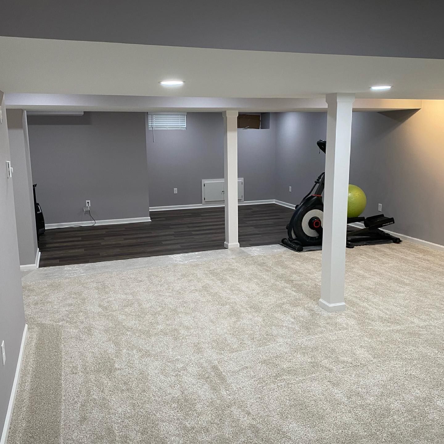 A basement with a exercise bike and a pilates ball.
