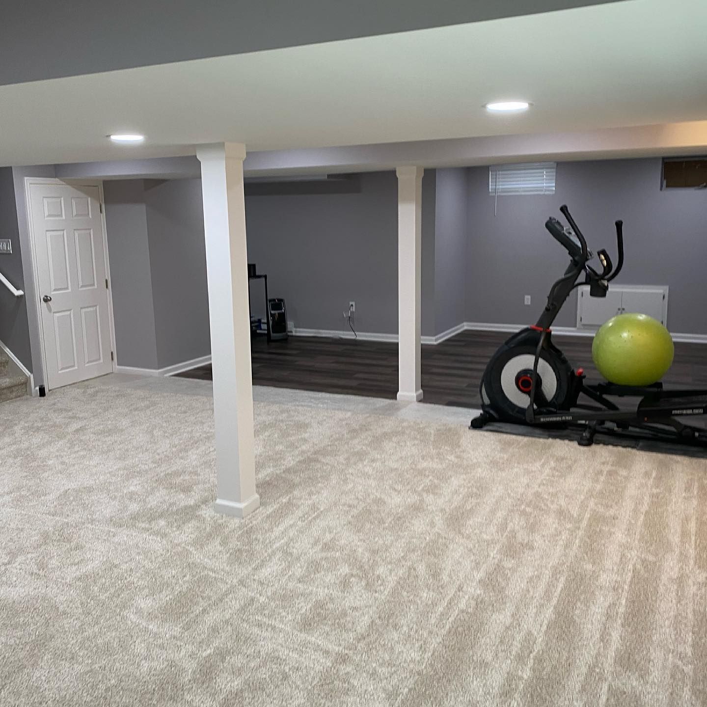 A basement with a exercise bike and a pilates ball.