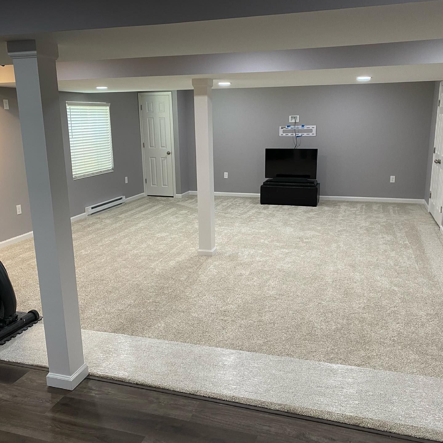 A basement with a carpeted floor and a flat screen tv.