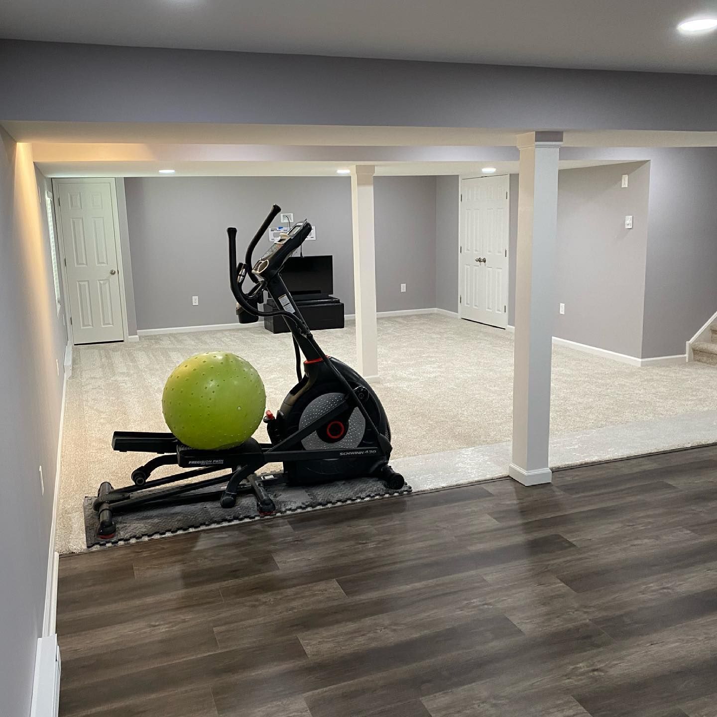 An elliptical machine and a ball are in a basement.