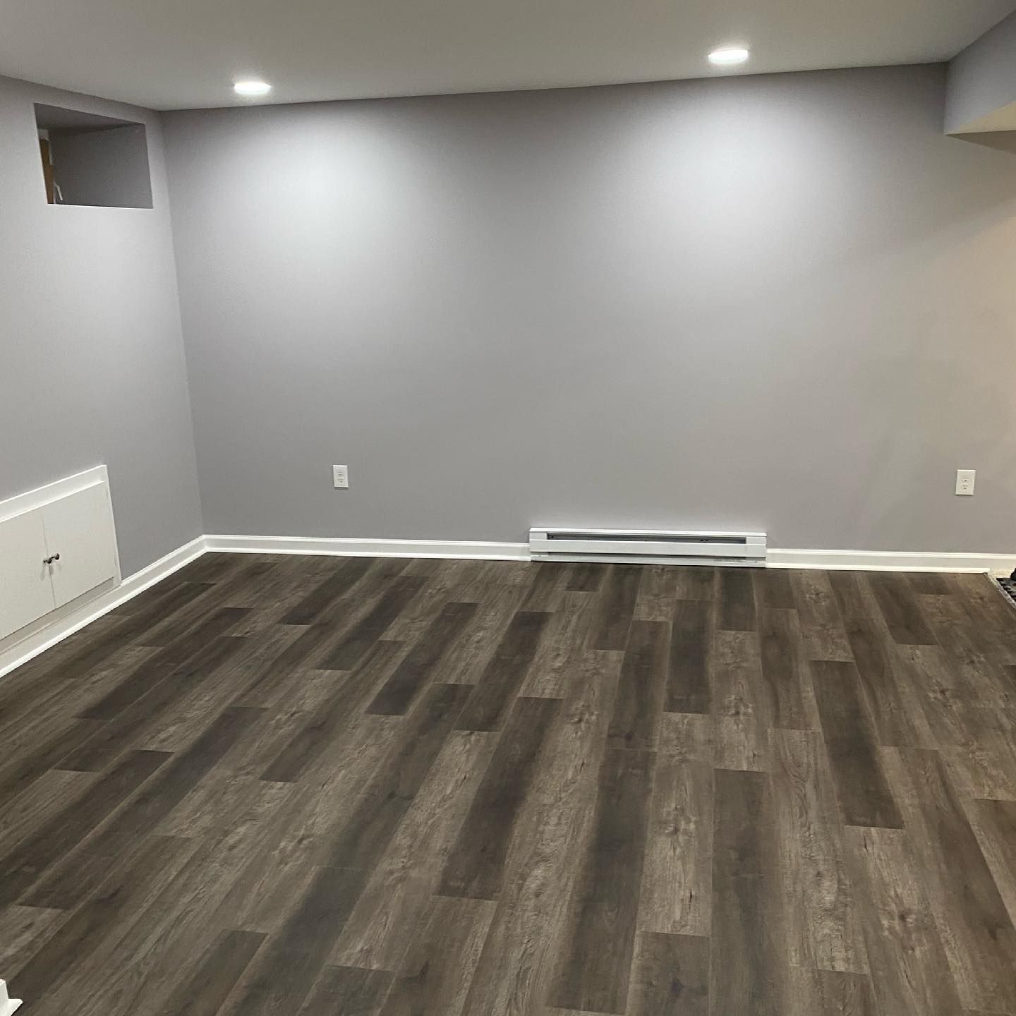 An empty room with a wooden floor and gray walls.