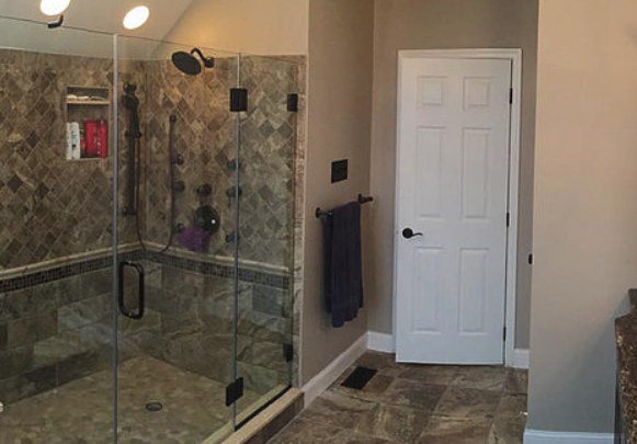 A bathroom with a walk in shower and a white door.