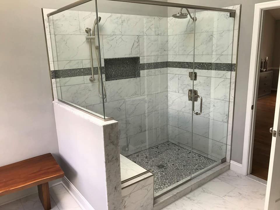 A bathroom with a walk in shower and a bench.