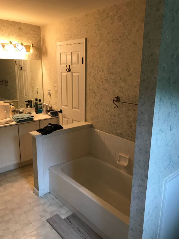 A bathroom with a bathtub , sink , mirror and door.