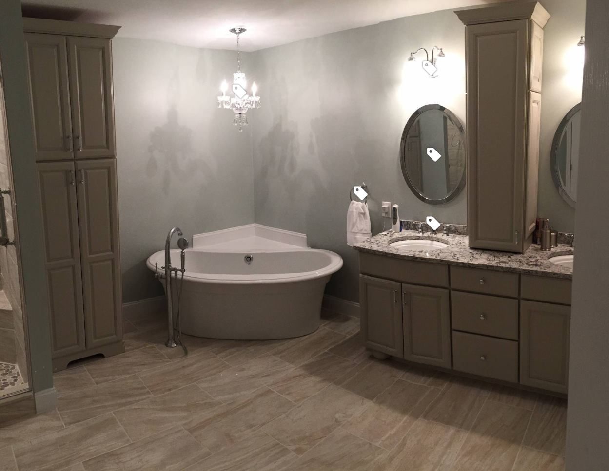 A bathroom with a tub , sinks , mirrors and cabinets.
