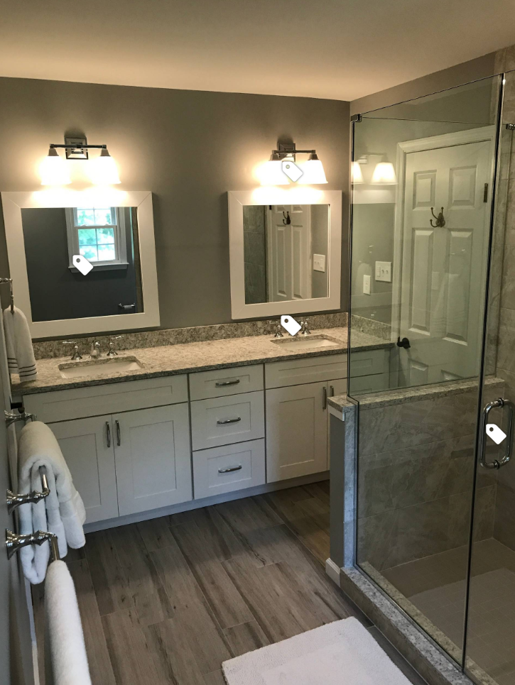 A bathroom with two sinks , two mirrors and a walk in shower.