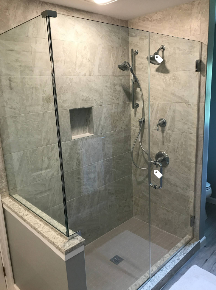 A bathroom with a walk in shower with a glass door.