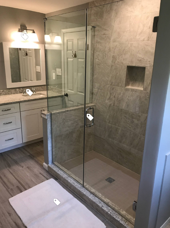 A bathroom with a walk in shower , sink and mirror.