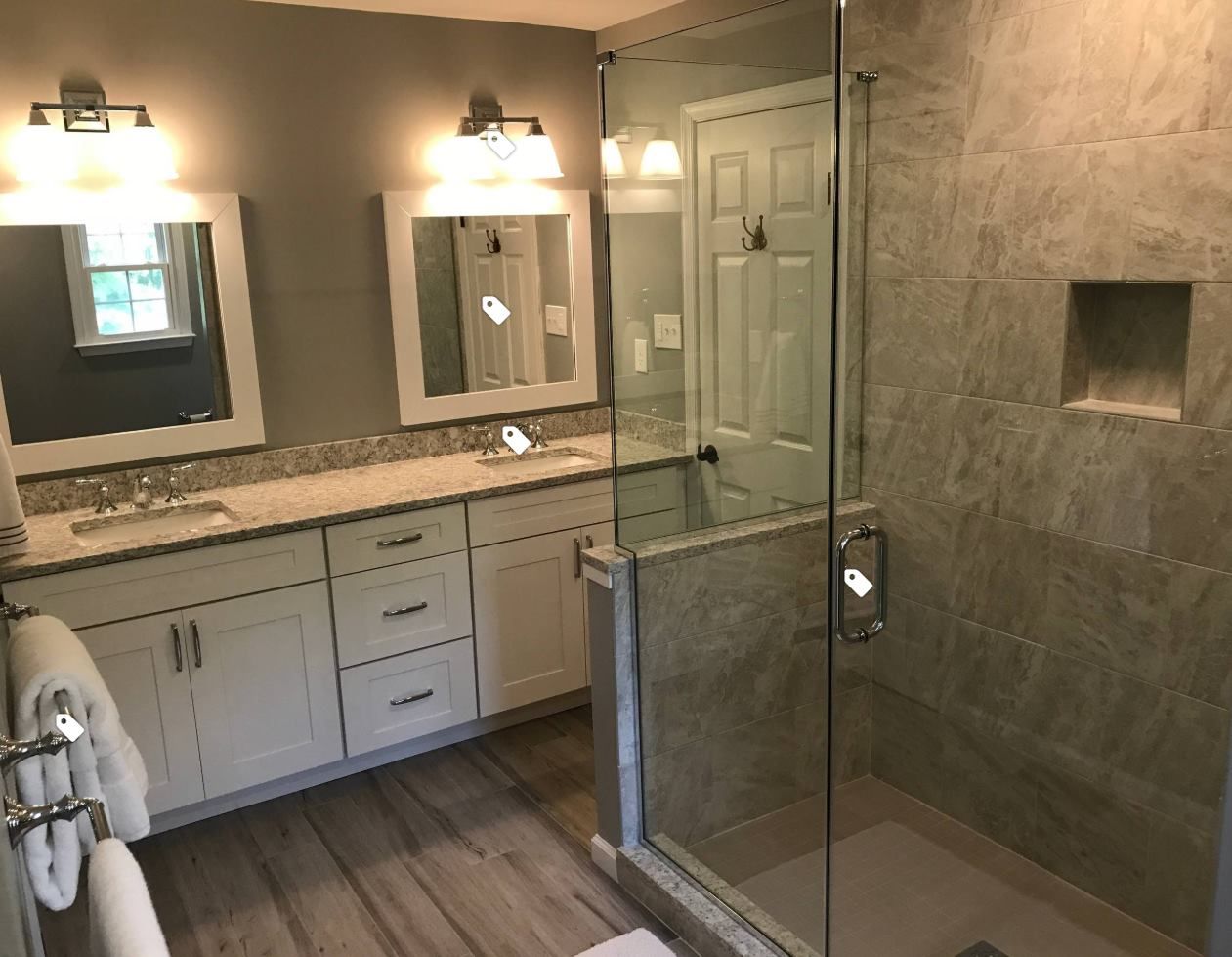 A bathroom with two sinks and a walk in shower.