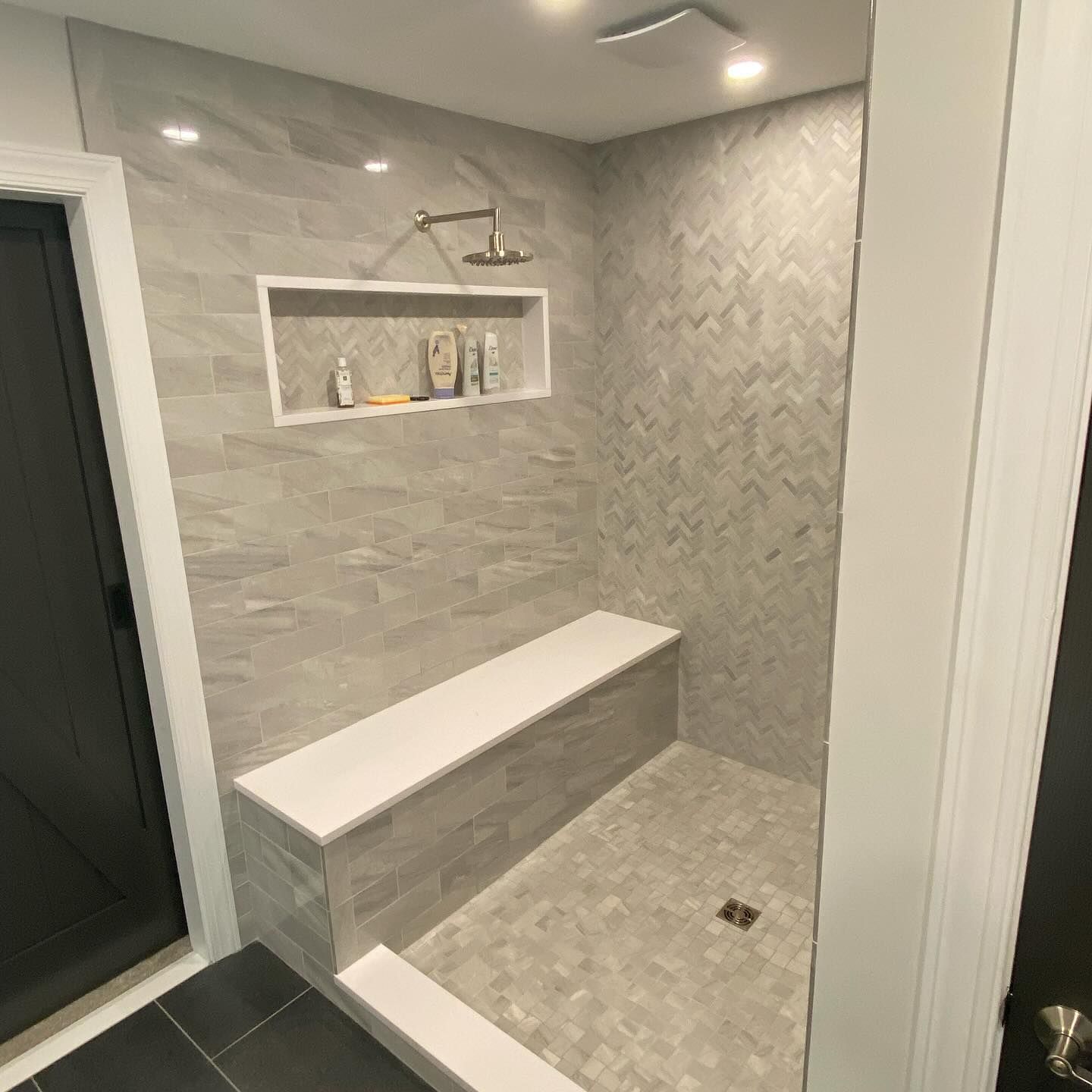 A bathroom with a walk in shower and a bench.
