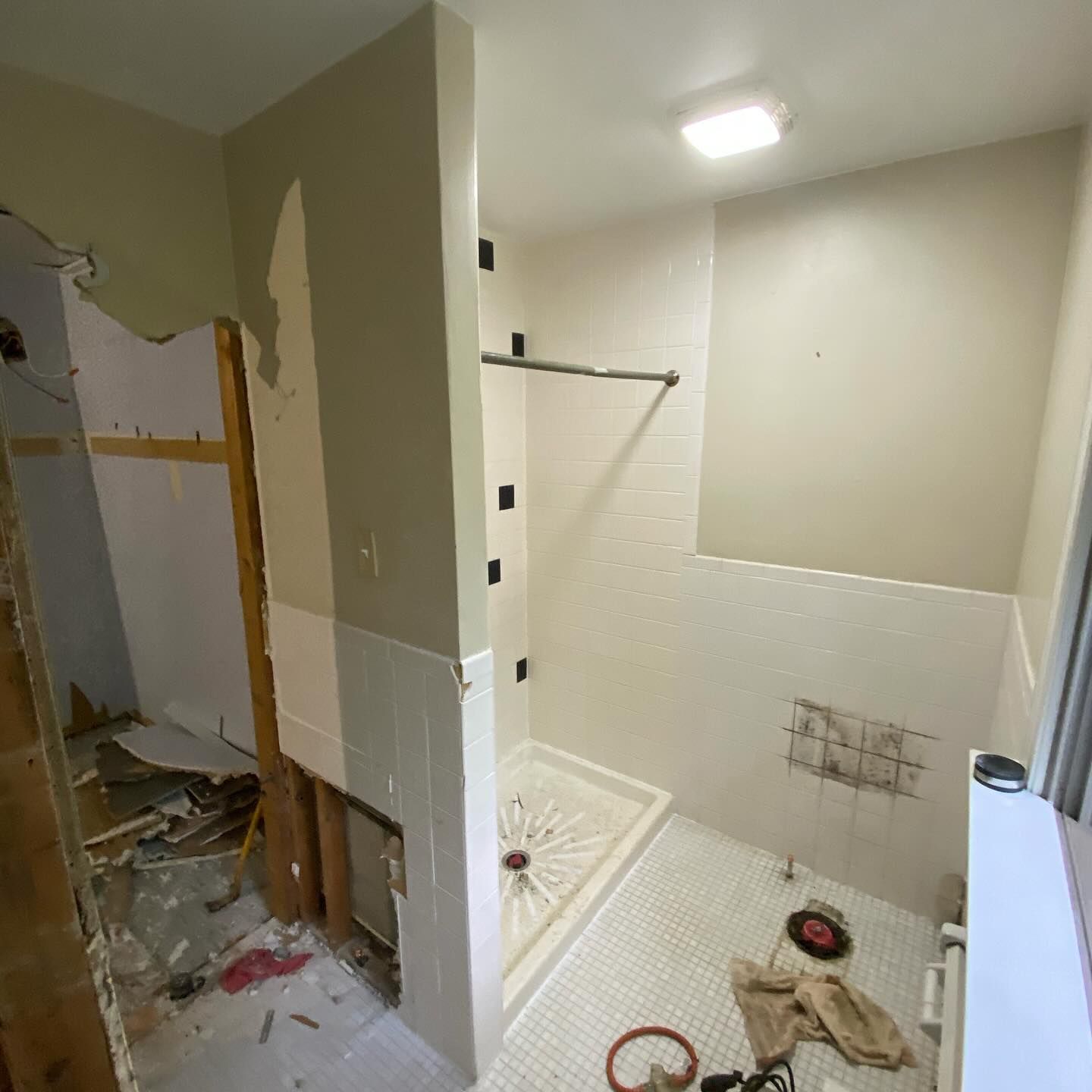 A bathroom under construction with a shower stall and a window.