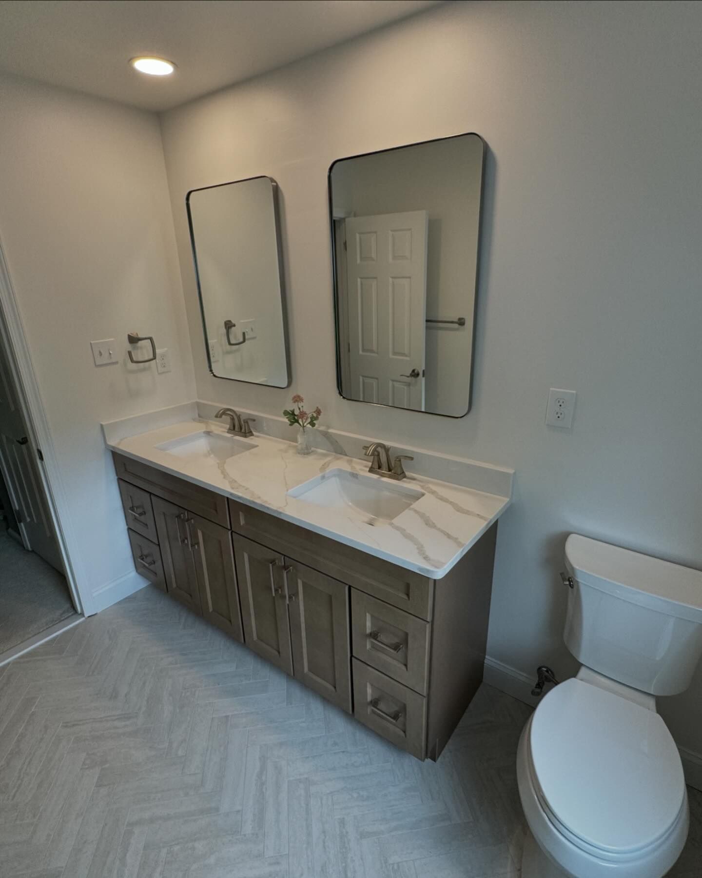 A bathroom with two sinks , two mirrors and a toilet.