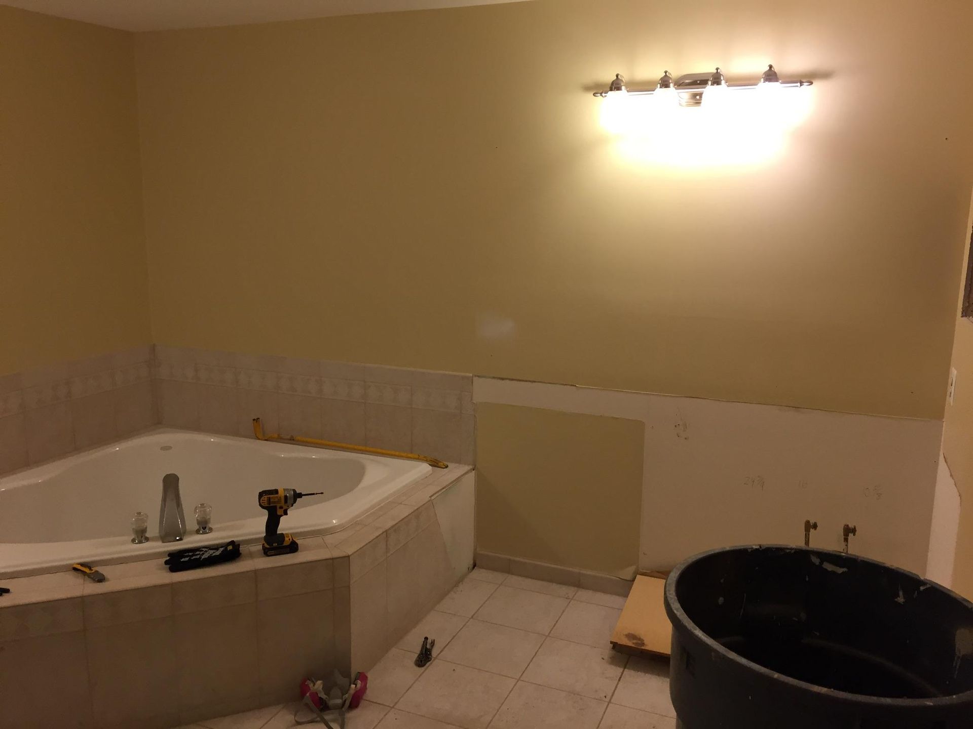 A bathroom with a jacuzzi tub and a trash can.