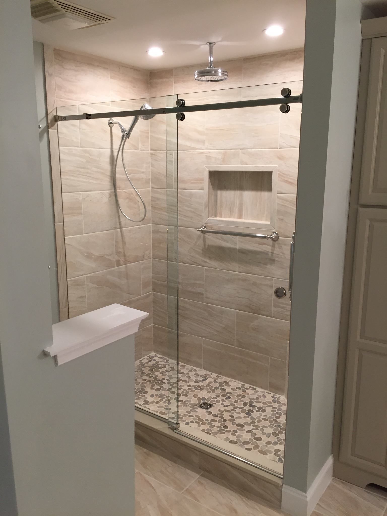 A bathroom with a sliding glass shower door and a shower head.
