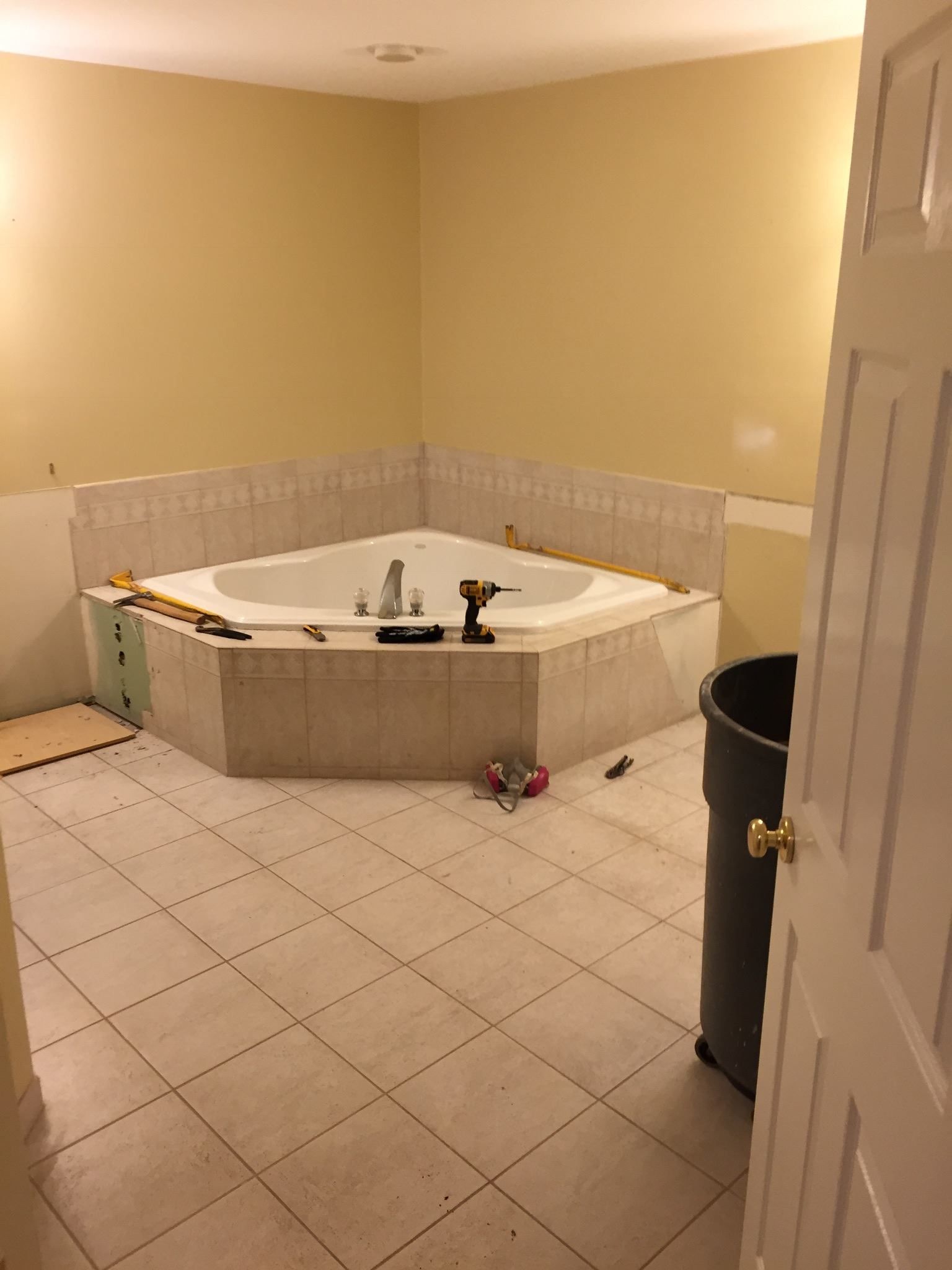 A bathroom with a jacuzzi tub and a trash can