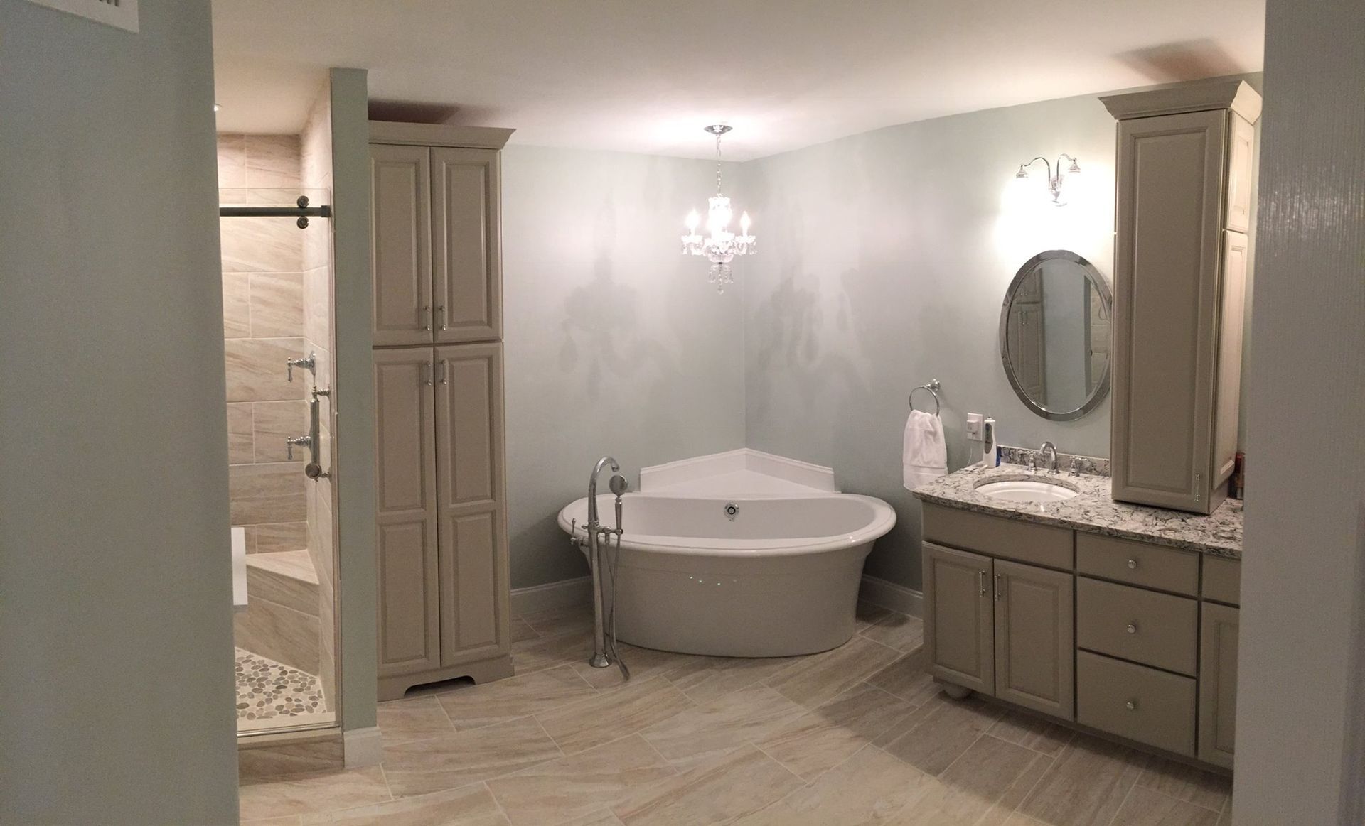 A bathroom with a tub , sink , mirror and cabinets.