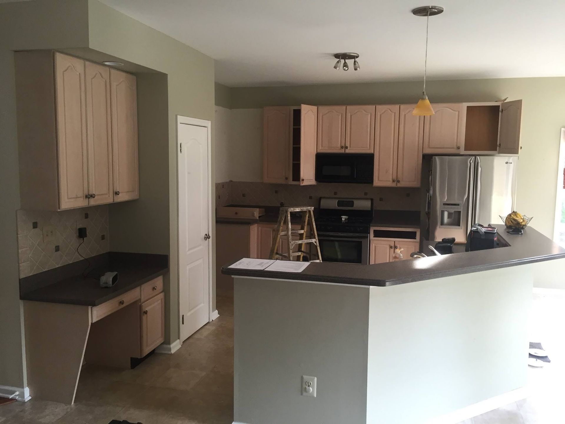 A kitchen with a ladder on the counter and a refrigerator.