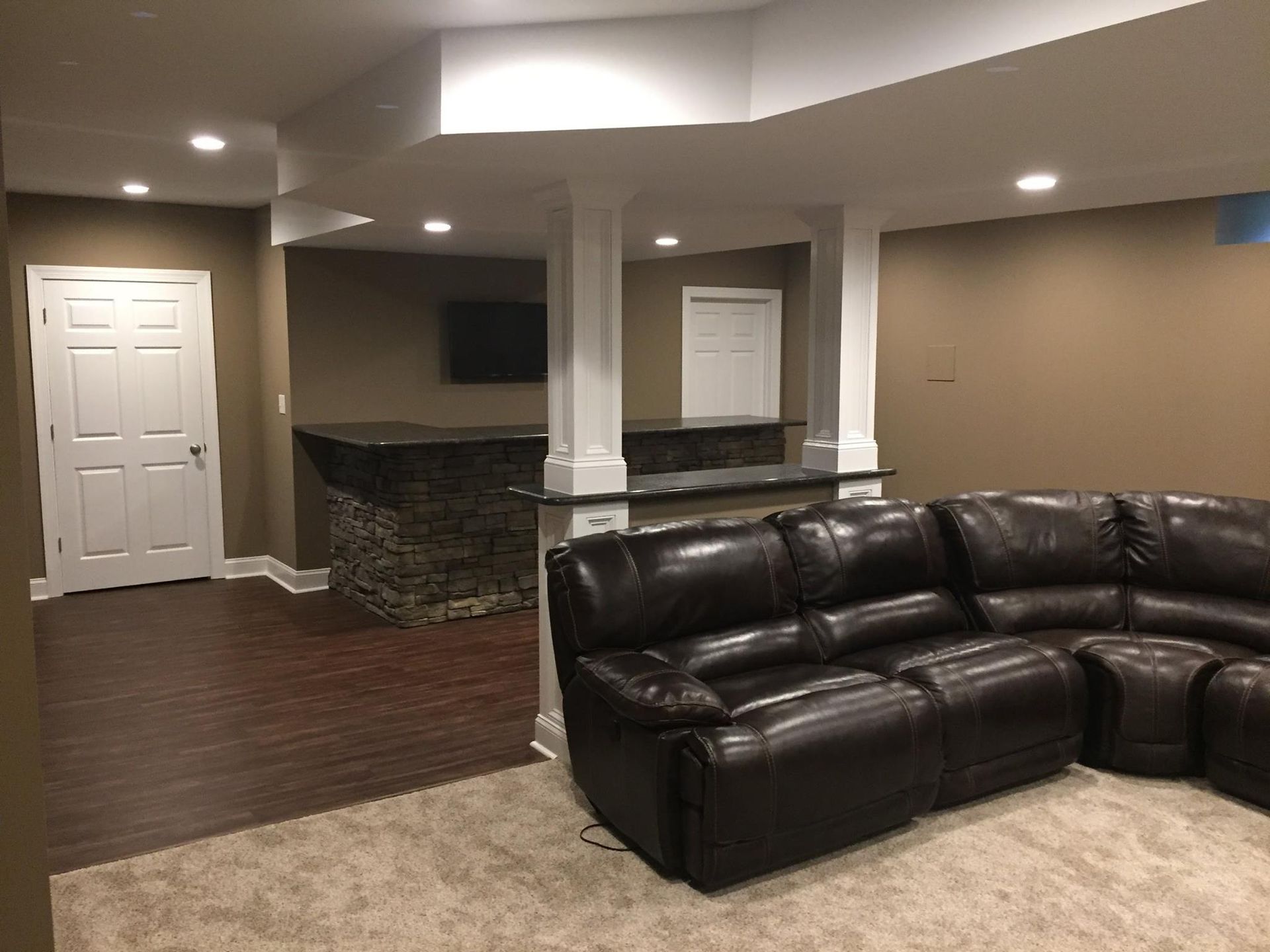 A living room in a basement with a couch and a bar.