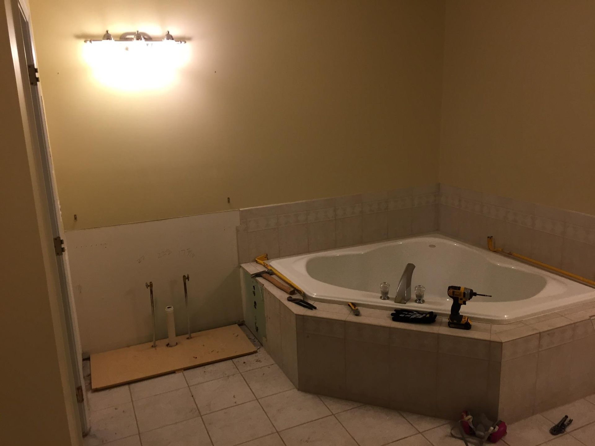 A bathroom with a jacuzzi tub and a drill on the floor.