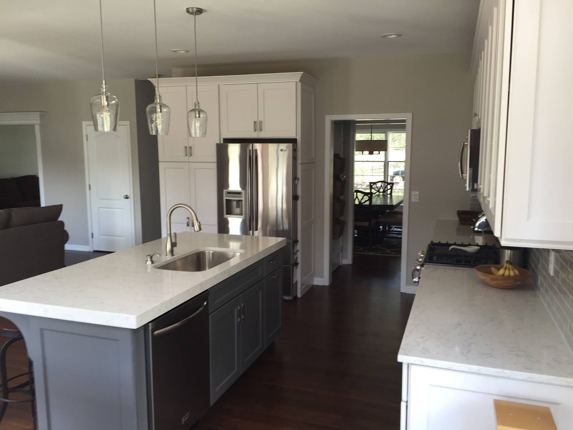 A kitchen with a large island and a stainless steel refrigerator